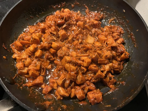 Jackfruit in der Pfanne mit Achiote-Sauce beim Einkochen, bevor sie als Tacos serviert werden.